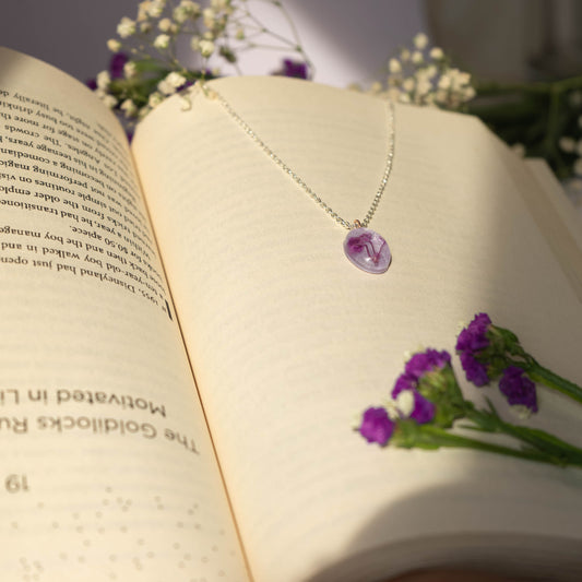 A collection of handmade resin art pendants, showcasing intricate floral designs preserved in clear resin, attached to delicate necklaces.