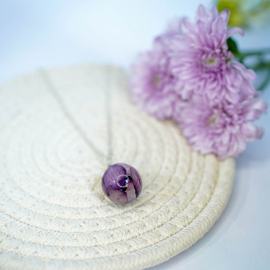 A collection of handmade resin art pendants, showcasing intricate floral designs preserved in clear resin, attached to delicate necklaces.