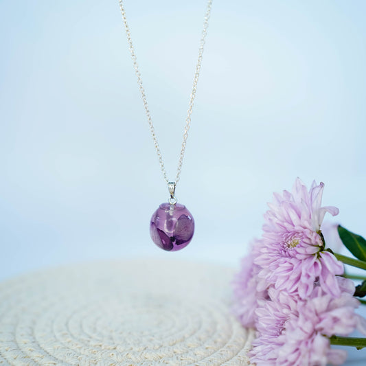 A collection of handmade resin art pendants, showcasing intricate floral designs preserved in clear resin, attached to delicate necklaces.