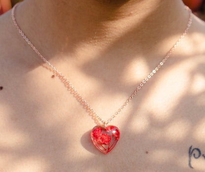 A collection of handmade resin art pendants, showcasing intricate floral designs preserved in clear resin, attached to delicate necklaces.