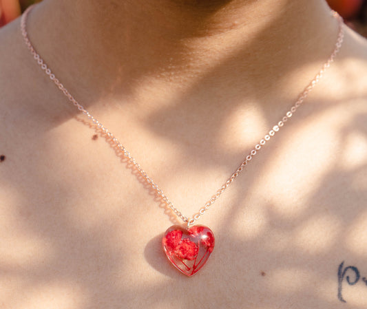 A collection of handmade resin art pendants, showcasing intricate floral designs preserved in clear resin, attached to delicate necklaces.
