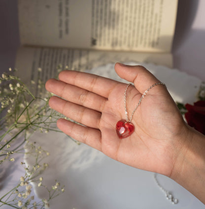 A collection of handmade resin art pendants, showcasing intricate floral designs preserved in clear resin, attached to delicate necklaces.