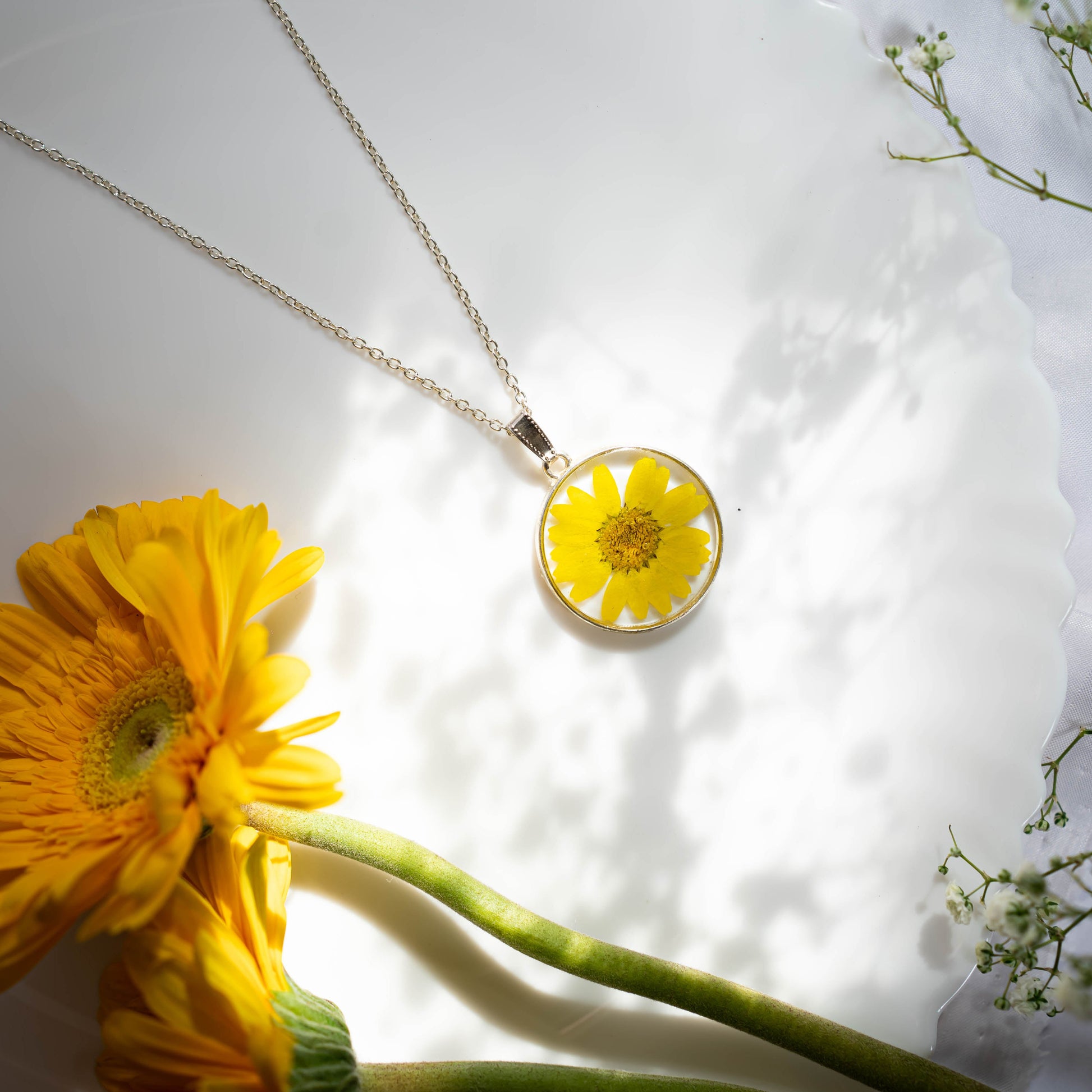 A collection of handmade resin art pendants, showcasing intricate floral designs preserved in clear resin, attached to delicate necklaces.