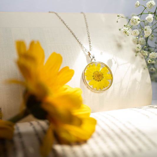 A collection of handmade resin art pendants, showcasing intricate floral designs preserved in clear resin, attached to delicate necklaces.