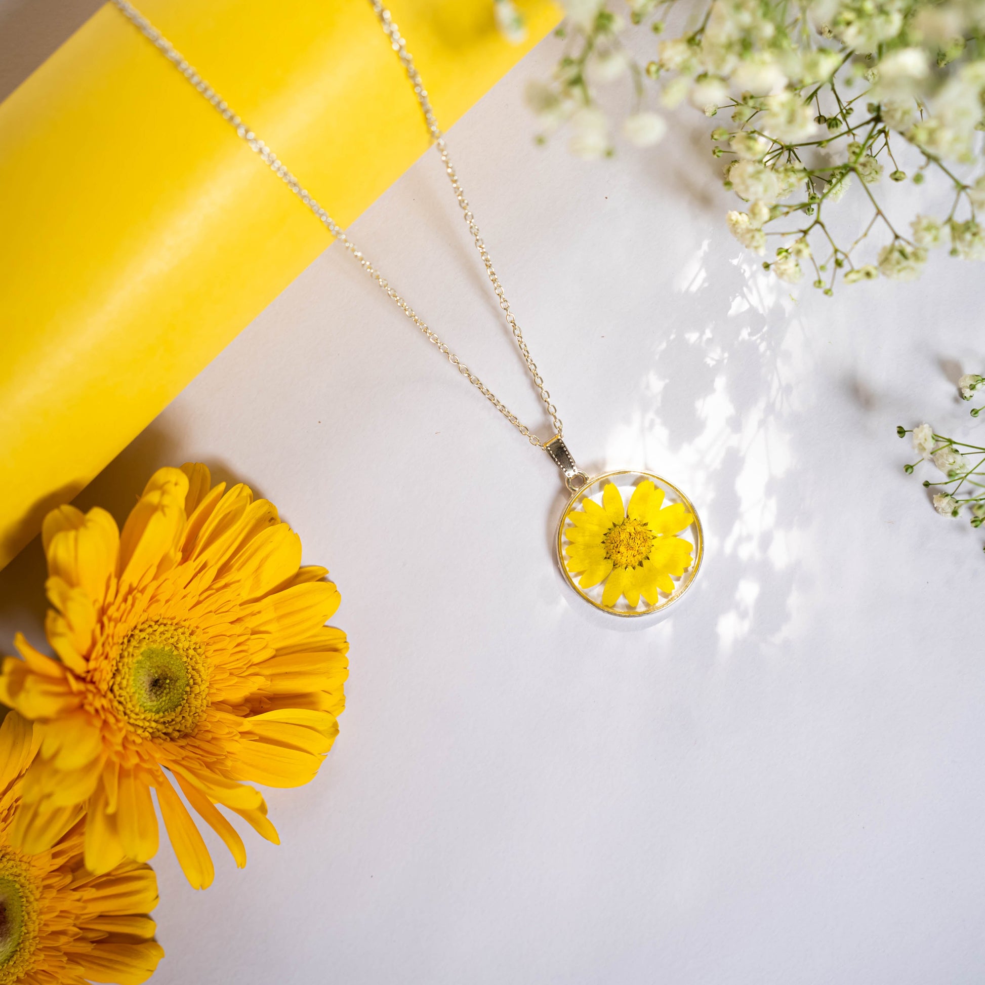 A collection of handmade resin art pendants, showcasing intricate floral designs preserved in clear resin, attached to delicate necklaces.
