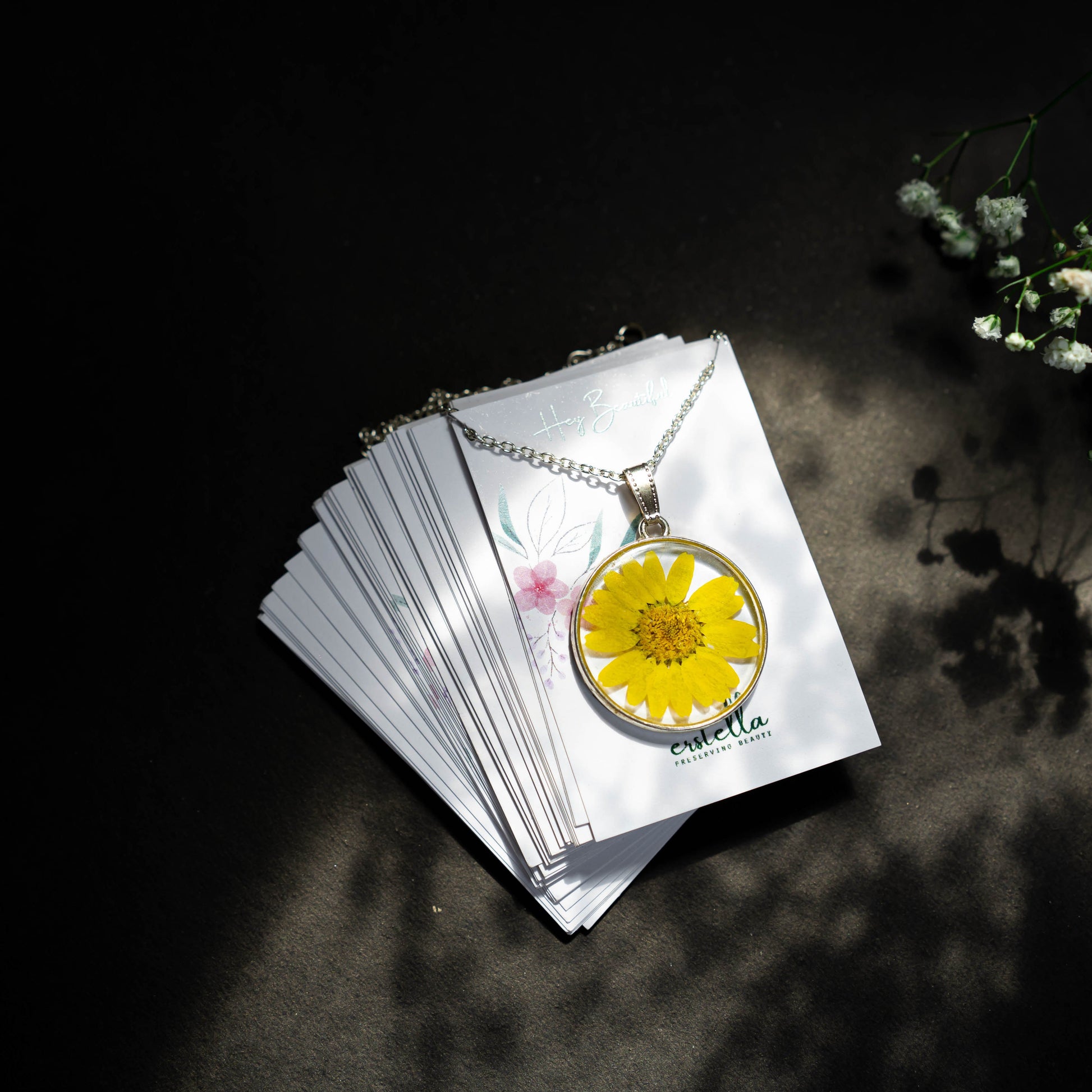 A collection of handmade resin art pendants, showcasing intricate floral designs preserved in clear resin, attached to delicate necklaces.