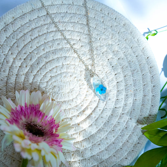 A collection of handmade resin art pendants, showcasing intricate floral designs preserved in clear resin, attached to delicate necklaces.