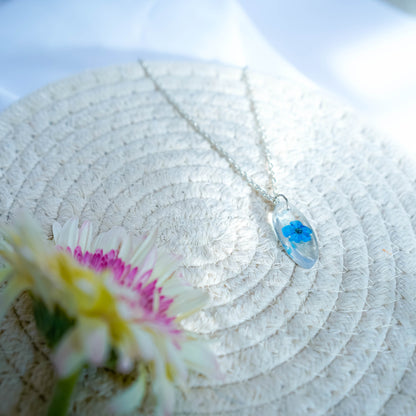 A collection of handmade resin art pendants, showcasing intricate floral designs preserved in clear resin, attached to delicate necklaces.