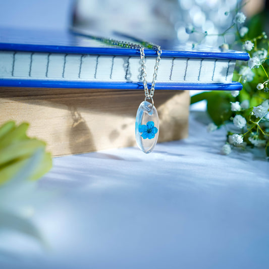 A collection of handmade resin art pendants, showcasing intricate floral designs preserved in clear resin, attached to delicate necklaces.