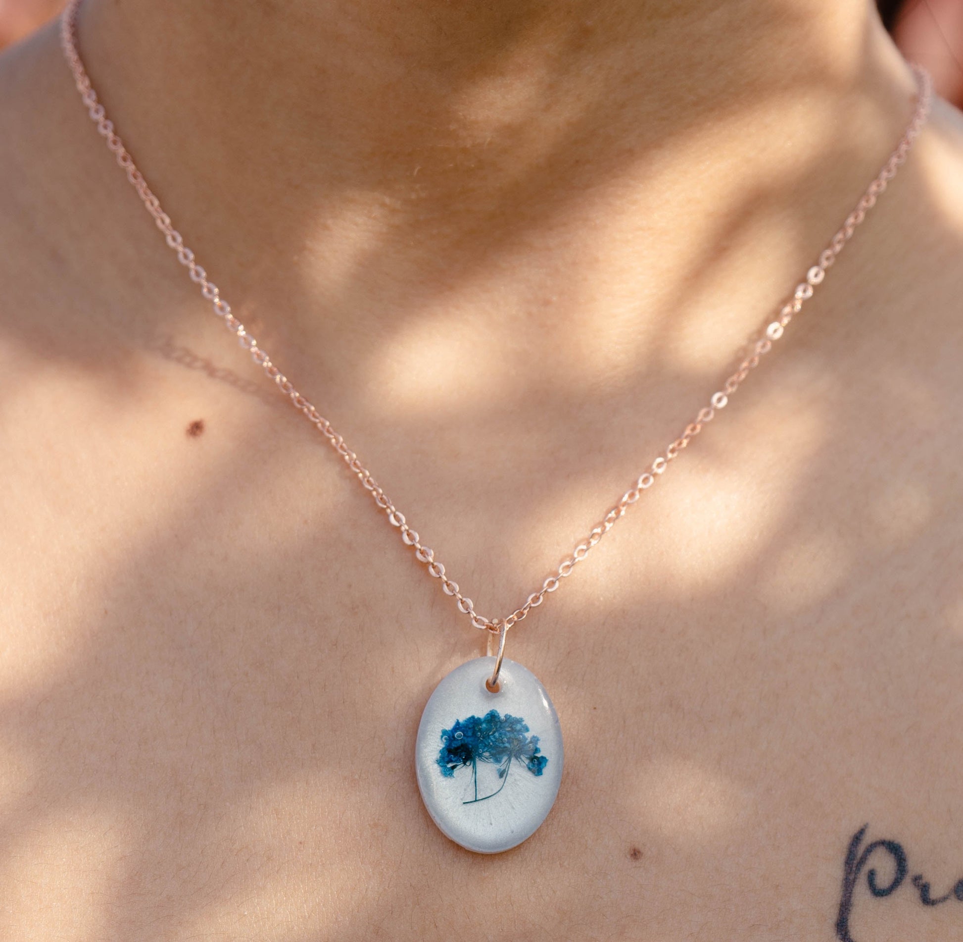 A collection of handmade resin art pendants, showcasing intricate floral designs preserved in clear resin, attached to delicate necklaces.
