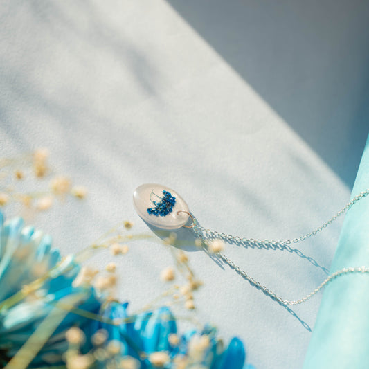 A collection of handmade resin art pendants, showcasing intricate floral designs preserved in clear resin, attached to delicate necklaces.