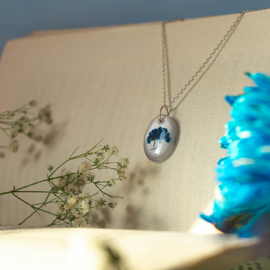 A collection of handmade resin art pendants, showcasing intricate floral designs preserved in clear resin, attached to delicate necklaces.