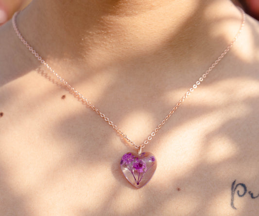 A collection of handmade resin art pendants, showcasing intricate floral designs preserved in clear resin, attached to delicate necklaces.