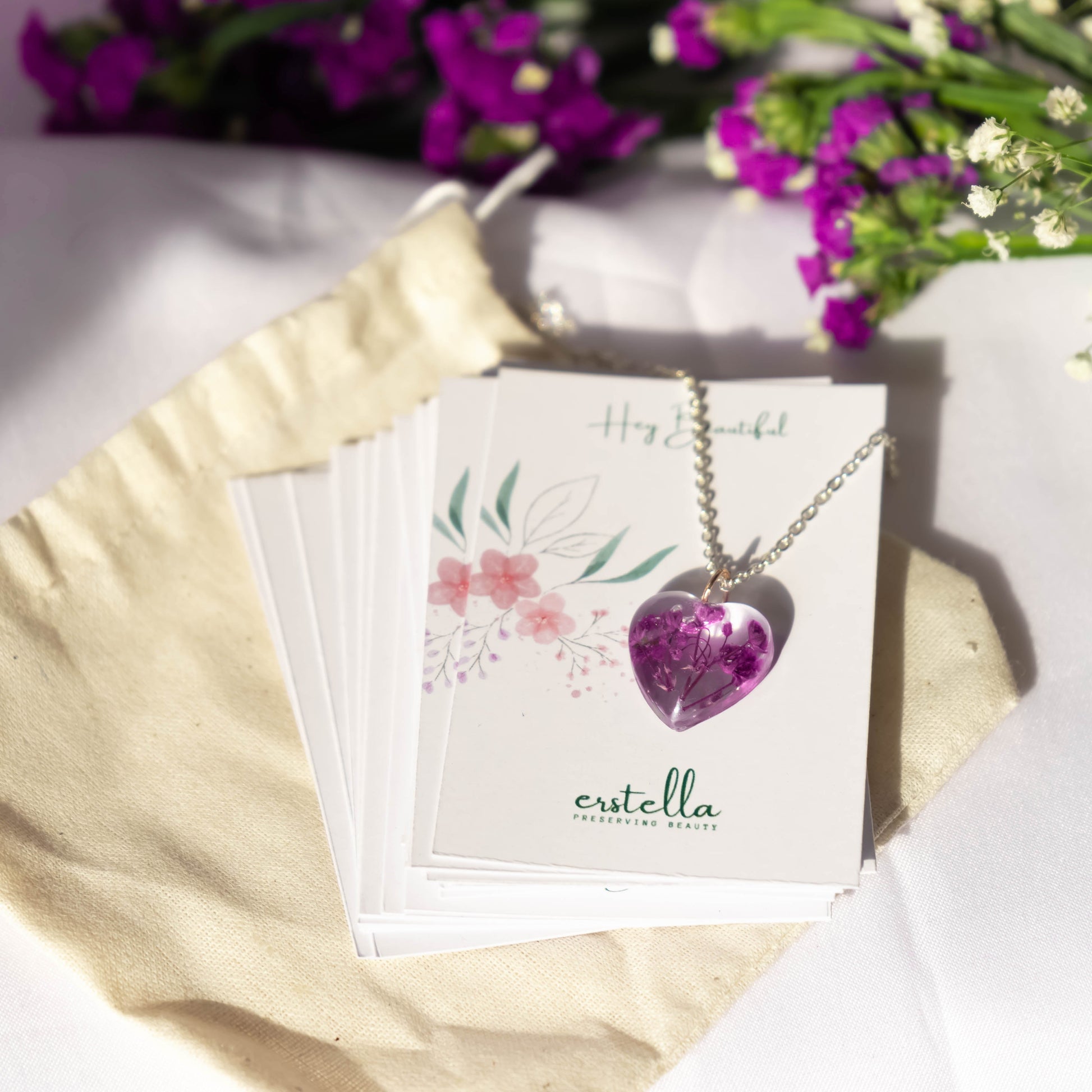 A collection of handmade resin art pendants, showcasing intricate floral designs preserved in clear resin, attached to delicate necklaces.