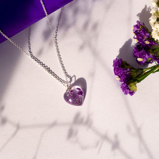 A collection of handmade resin art pendants, showcasing intricate floral designs preserved in clear resin, attached to delicate necklaces.