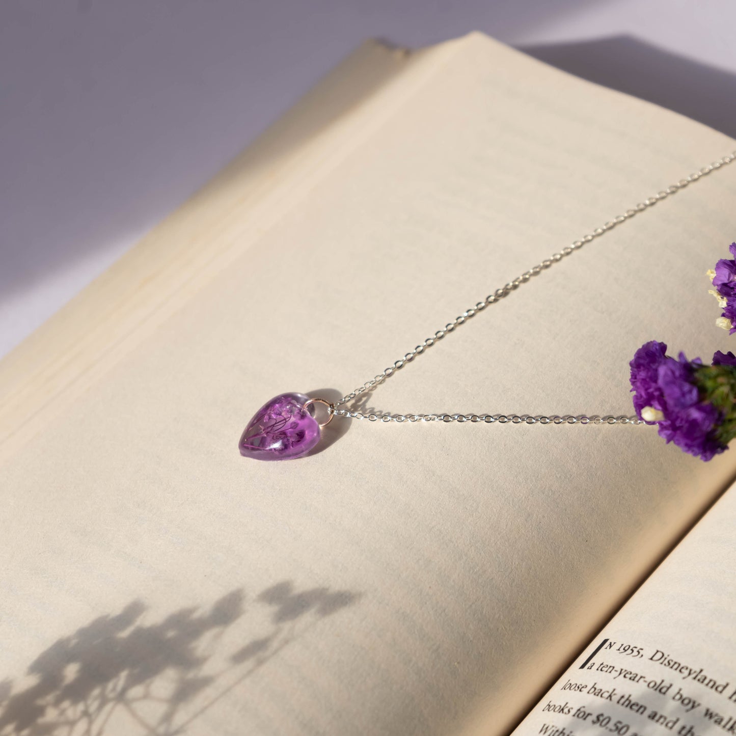 A collection of handmade resin art pendants, showcasing intricate floral designs preserved in clear resin, attached to delicate necklaces.
