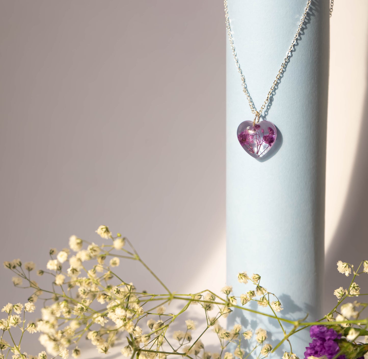 A collection of handmade resin art pendants, showcasing intricate floral designs preserved in clear resin, attached to delicate necklaces.