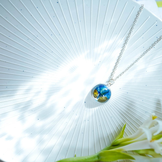 A collection of handmade resin art pendants, showcasing intricate floral designs preserved in clear resin, attached to delicate necklaces.