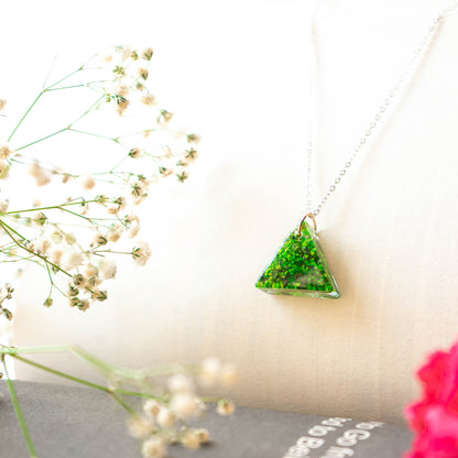 A collection of handmade resin art pendants, showcasing intricate floral designs preserved in clear resin, attached to delicate necklaces.