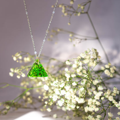 A collection of handmade resin art pendants, showcasing intricate floral designs preserved in clear resin, attached to delicate necklaces.