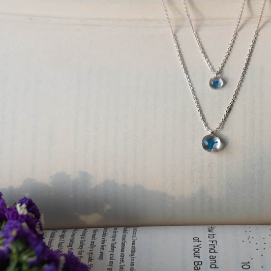A collection of handmade resin art pendants, showcasing intricate floral designs preserved in clear resin, attached to delicate necklaces.