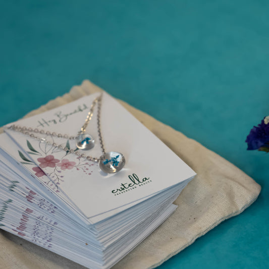 A collection of handmade resin art pendants, showcasing intricate floral designs preserved in clear resin, attached to delicate necklaces.