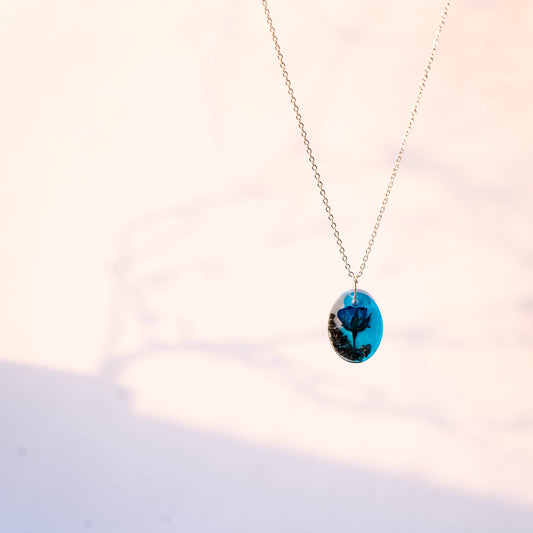 A collection of handmade resin art pendants, showcasing intricate floral designs preserved in clear resin, attached to delicate necklaces.