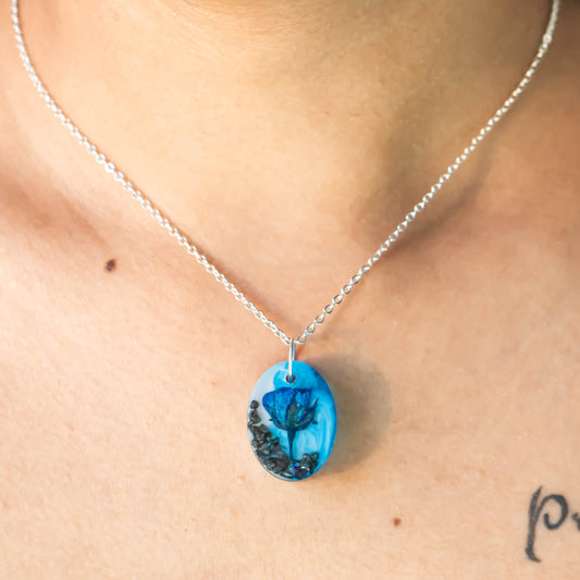A collection of handmade resin art pendants, showcasing intricate floral designs preserved in clear resin, attached to delicate necklaces.