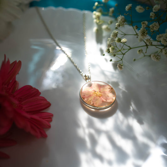 A collection of handmade resin art pendants, showcasing intricate floral designs preserved in clear resin, attached to delicate necklaces.