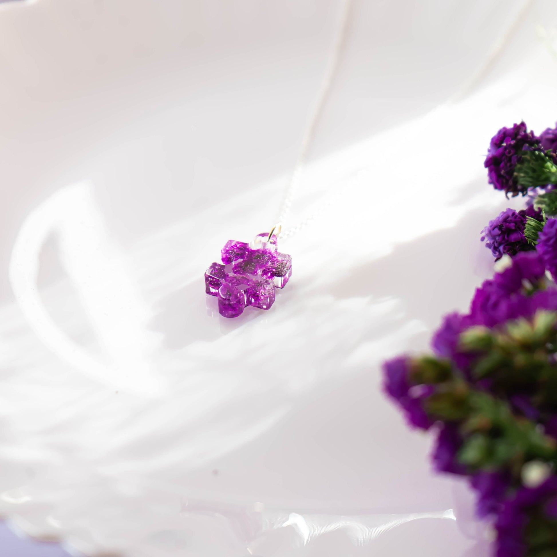 A collection of handmade resin art pendants, showcasing intricate floral designs preserved in clear resin, attached to delicate necklaces.