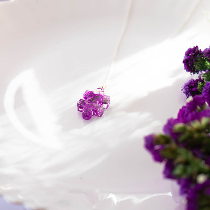A collection of handmade resin art pendants, showcasing intricate floral designs preserved in clear resin, attached to delicate necklaces.