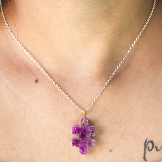 A collection of handmade resin art pendants, showcasing intricate floral designs preserved in clear resin, attached to delicate necklaces.