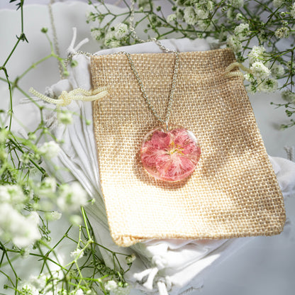 A collection of handmade resin art pendants, showcasing intricate floral designs preserved in clear resin, attached to delicate necklaces.