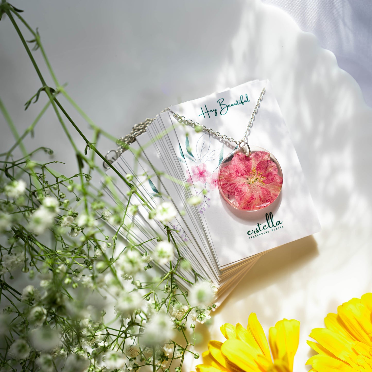 A collection of handmade resin art pendants, showcasing intricate floral designs preserved in clear resin, attached to delicate necklaces.