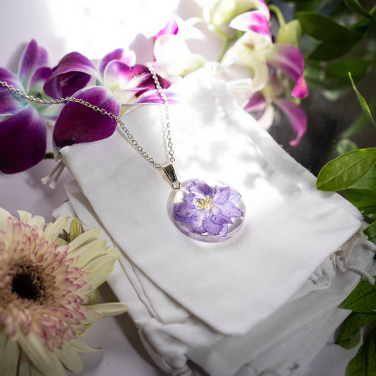 A collection of handmade resin art pendants, showcasing intricate floral designs preserved in clear resin, attached to delicate necklaces.
