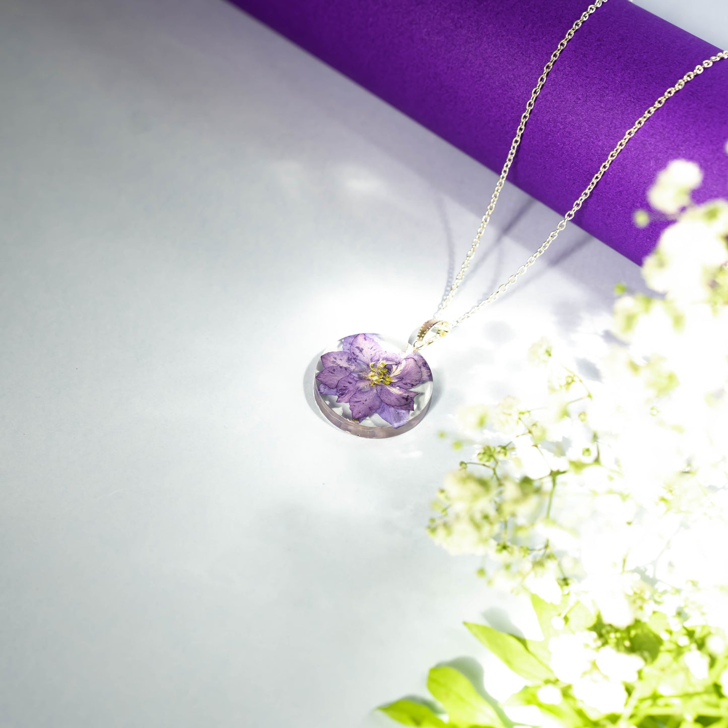 A collection of handmade resin art pendants, showcasing intricate floral designs preserved in clear resin, attached to delicate necklaces.