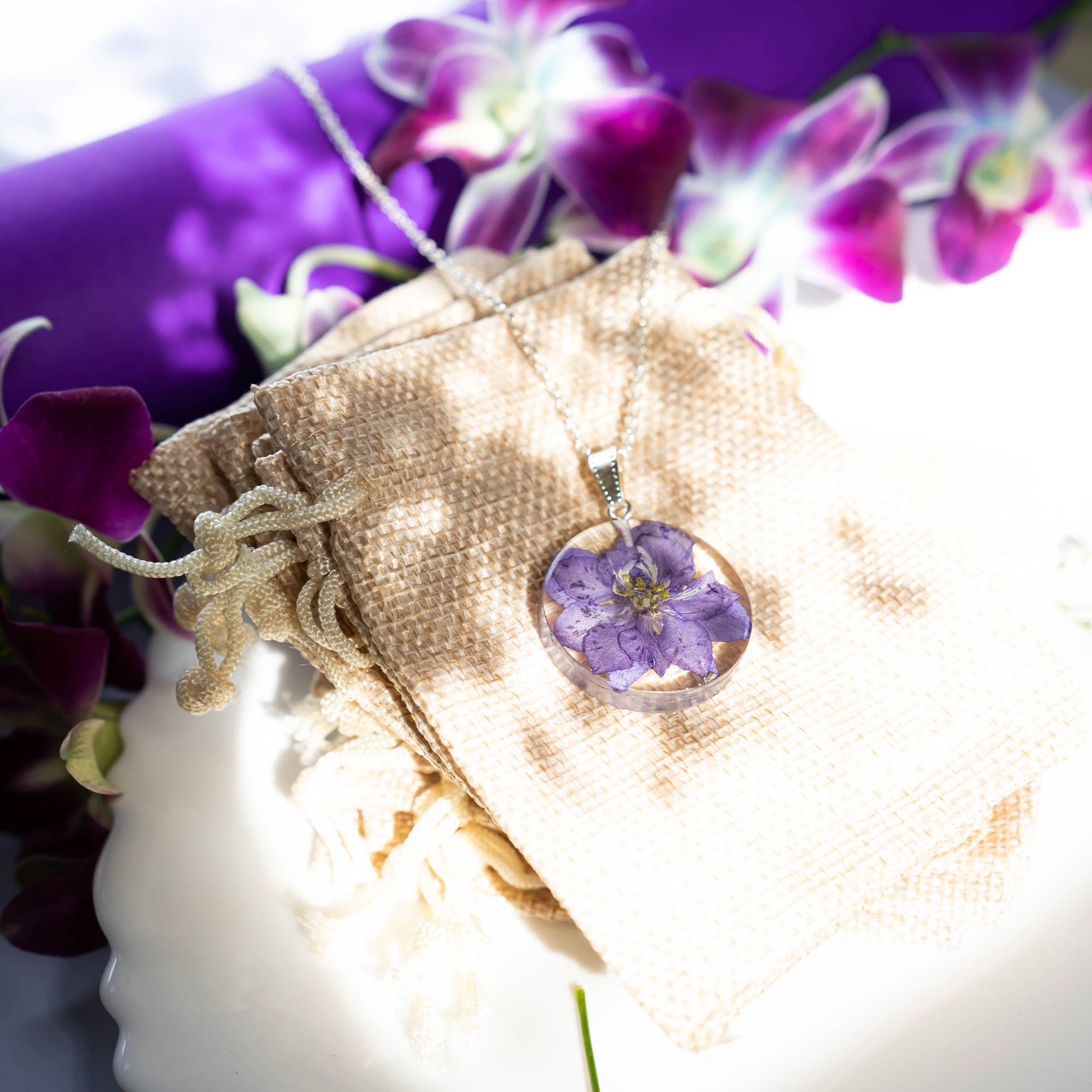 A collection of handmade resin art pendants, showcasing intricate floral designs preserved in clear resin, attached to delicate necklaces.