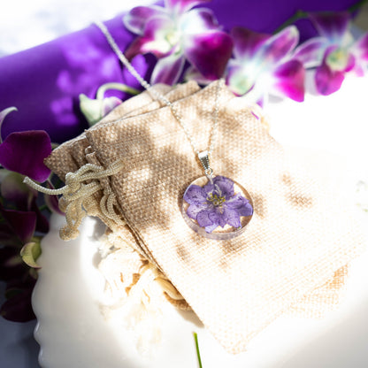 A collection of handmade resin art pendants, showcasing intricate floral designs preserved in clear resin, attached to delicate necklaces.