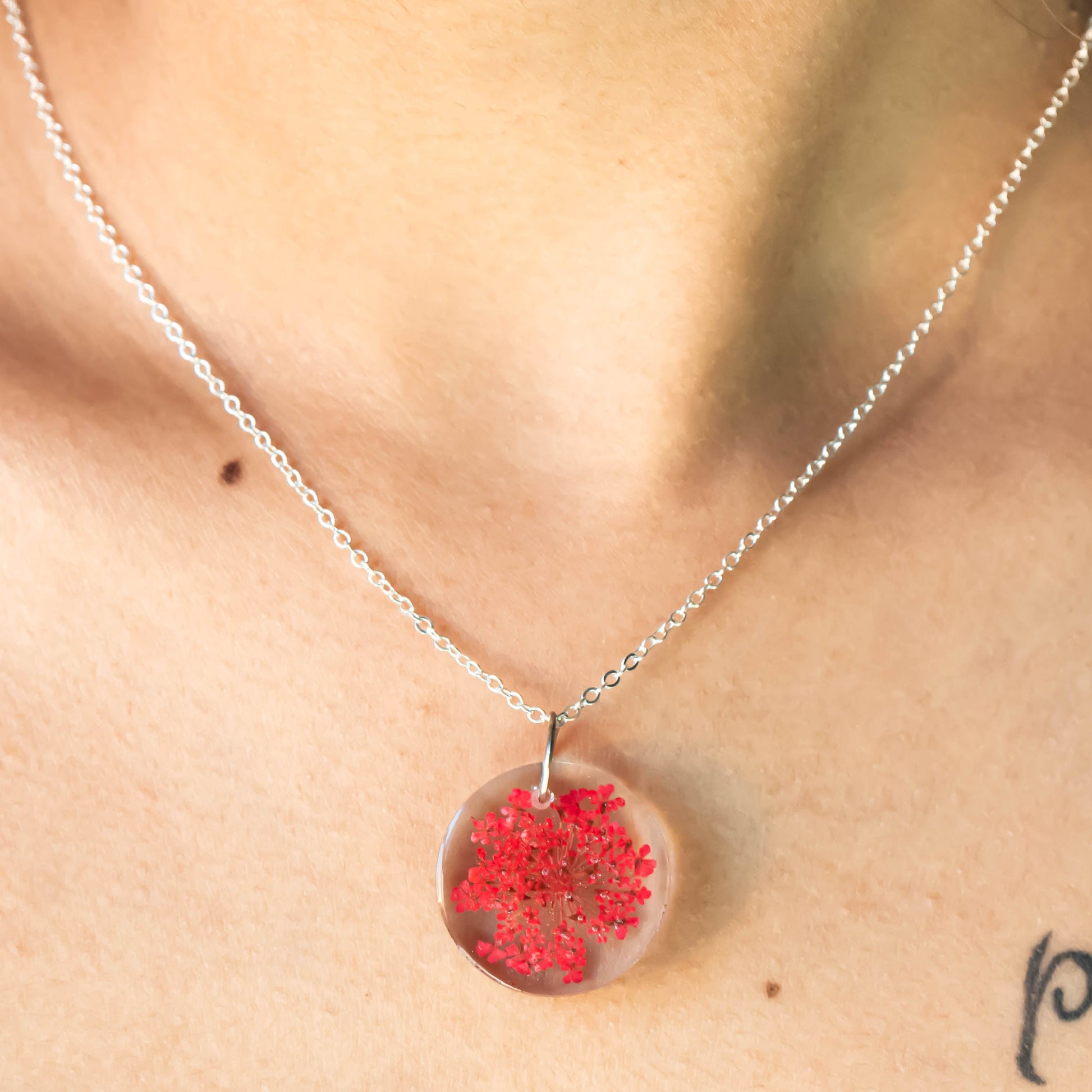A collection of handmade resin art pendants, showcasing intricate floral designs preserved in clear resin, attached to delicate necklaces.