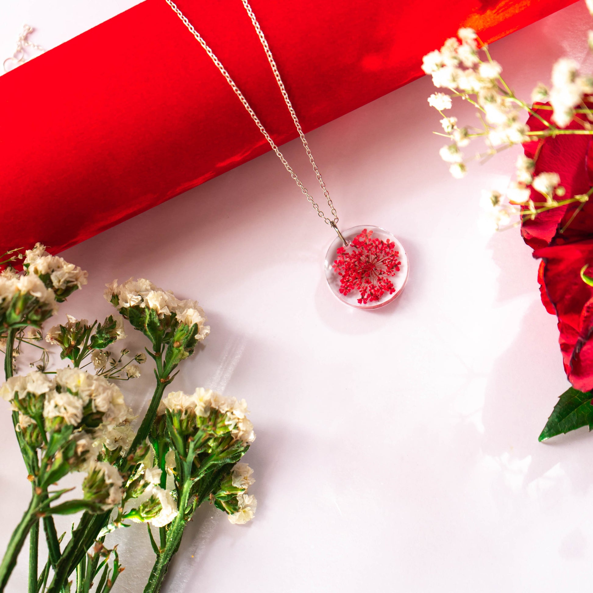 A collection of handmade resin art pendants, showcasing intricate floral designs preserved in clear resin, attached to delicate necklaces.