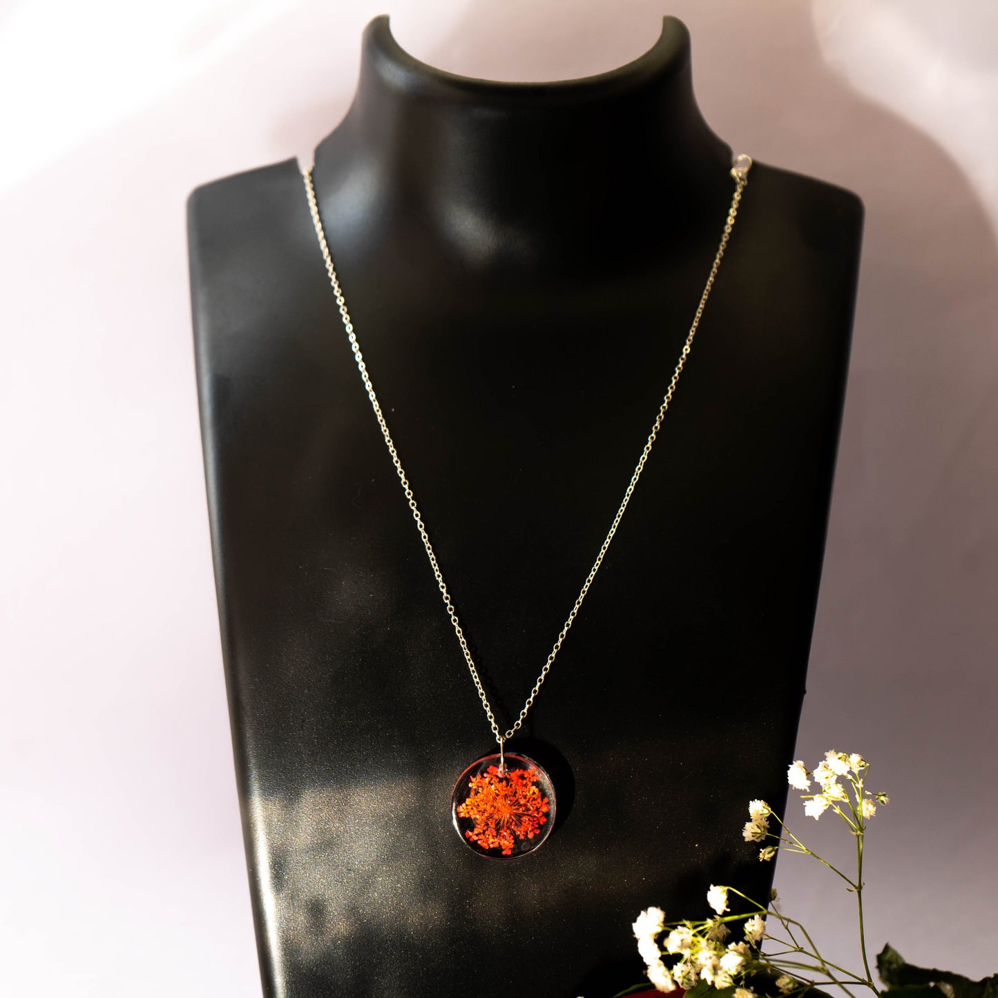 A collection of handmade resin art pendants, showcasing intricate floral designs preserved in clear resin, attached to delicate necklaces.