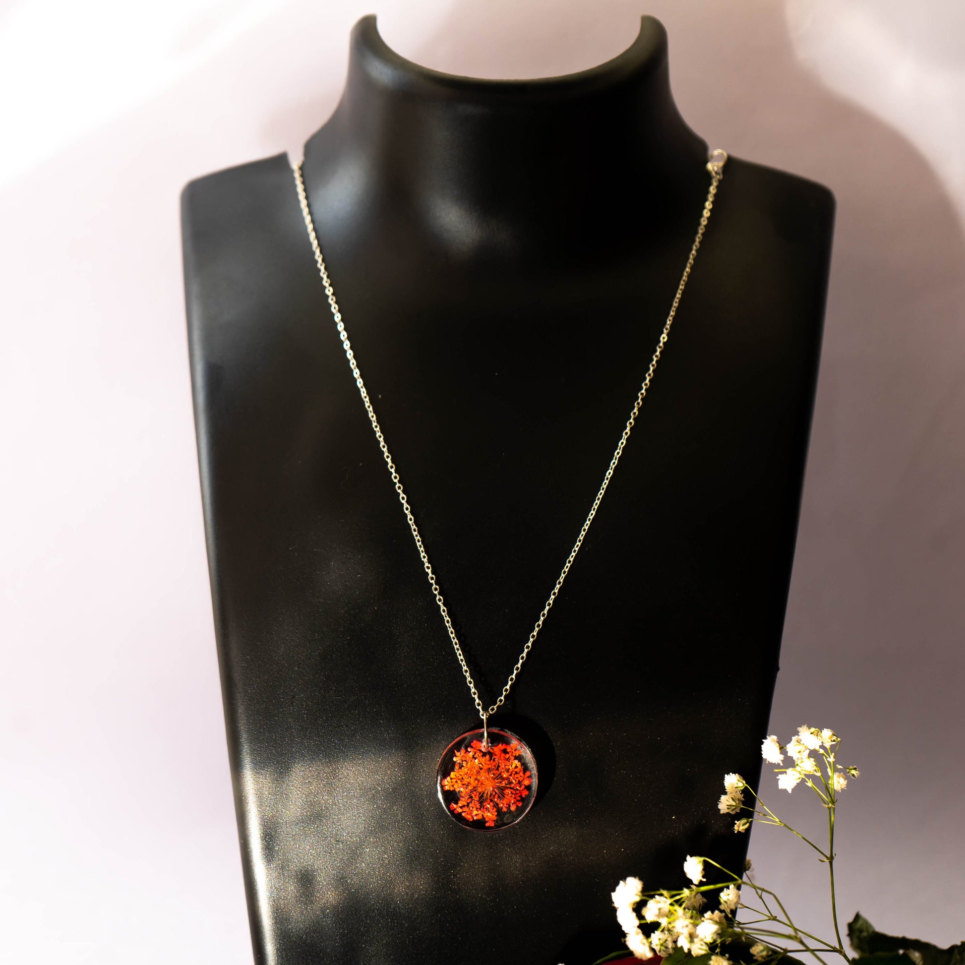 A collection of handmade resin art pendants, showcasing intricate floral designs preserved in clear resin, attached to delicate necklaces.