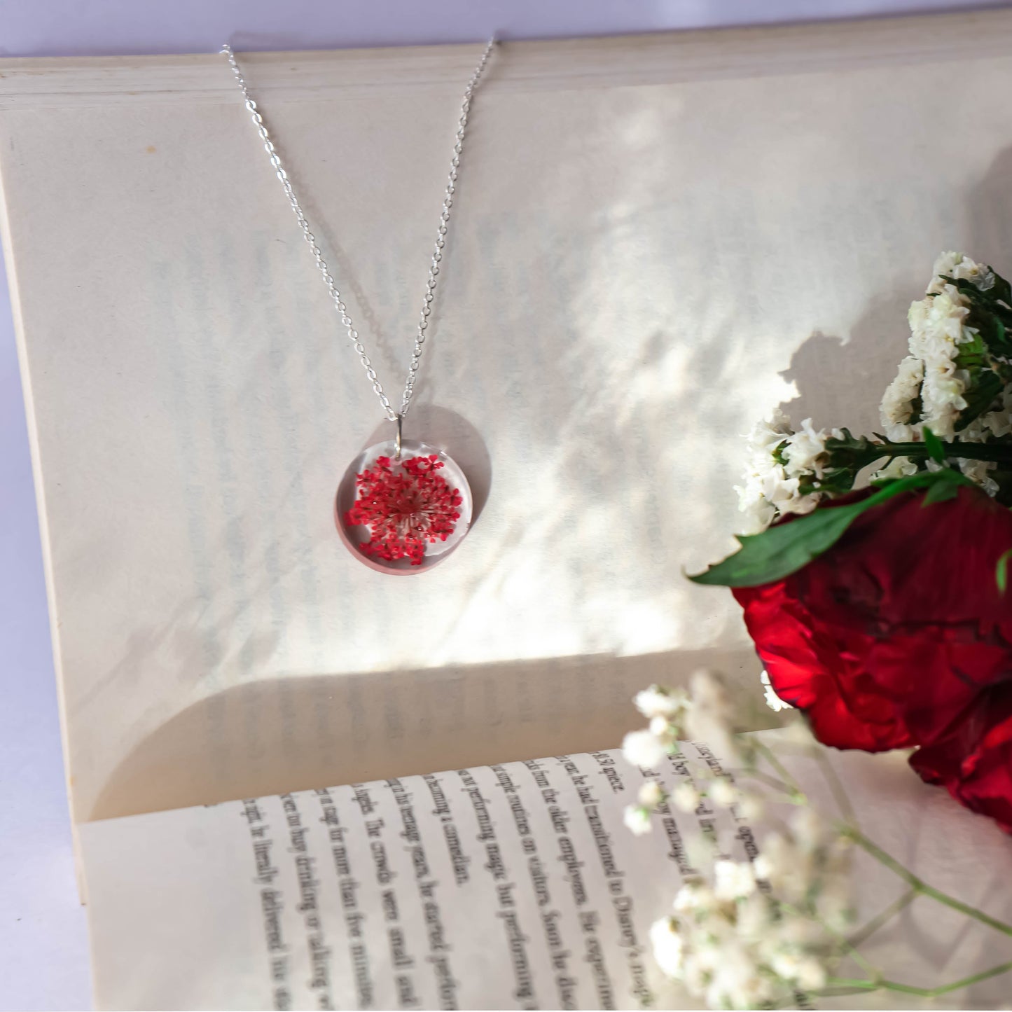 A collection of handmade resin art pendants, showcasing intricate floral designs preserved in clear resin, attached to delicate necklaces.