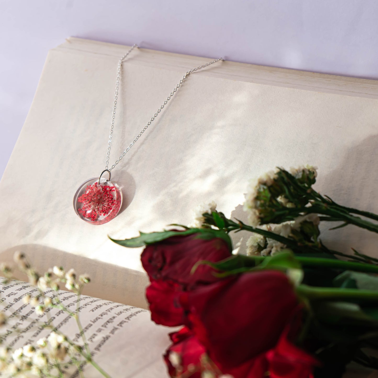 A collection of handmade resin art pendants, showcasing intricate floral designs preserved in clear resin, attached to delicate necklaces.
