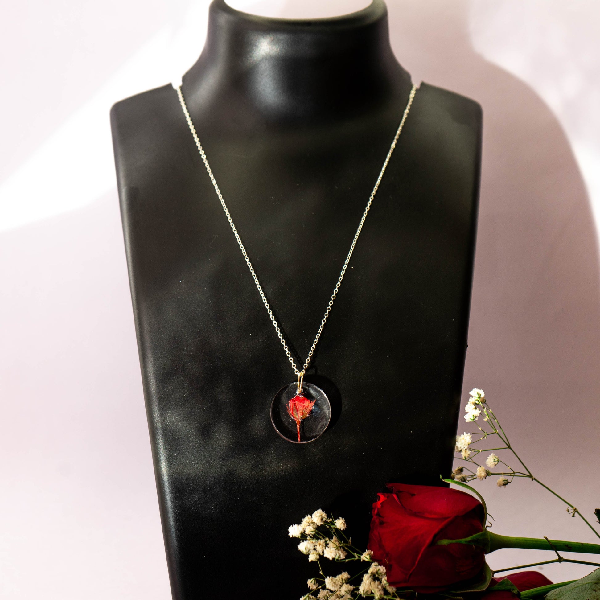A collection of handmade resin art pendants, showcasing intricate floral designs preserved in clear resin, attached to delicate necklaces.