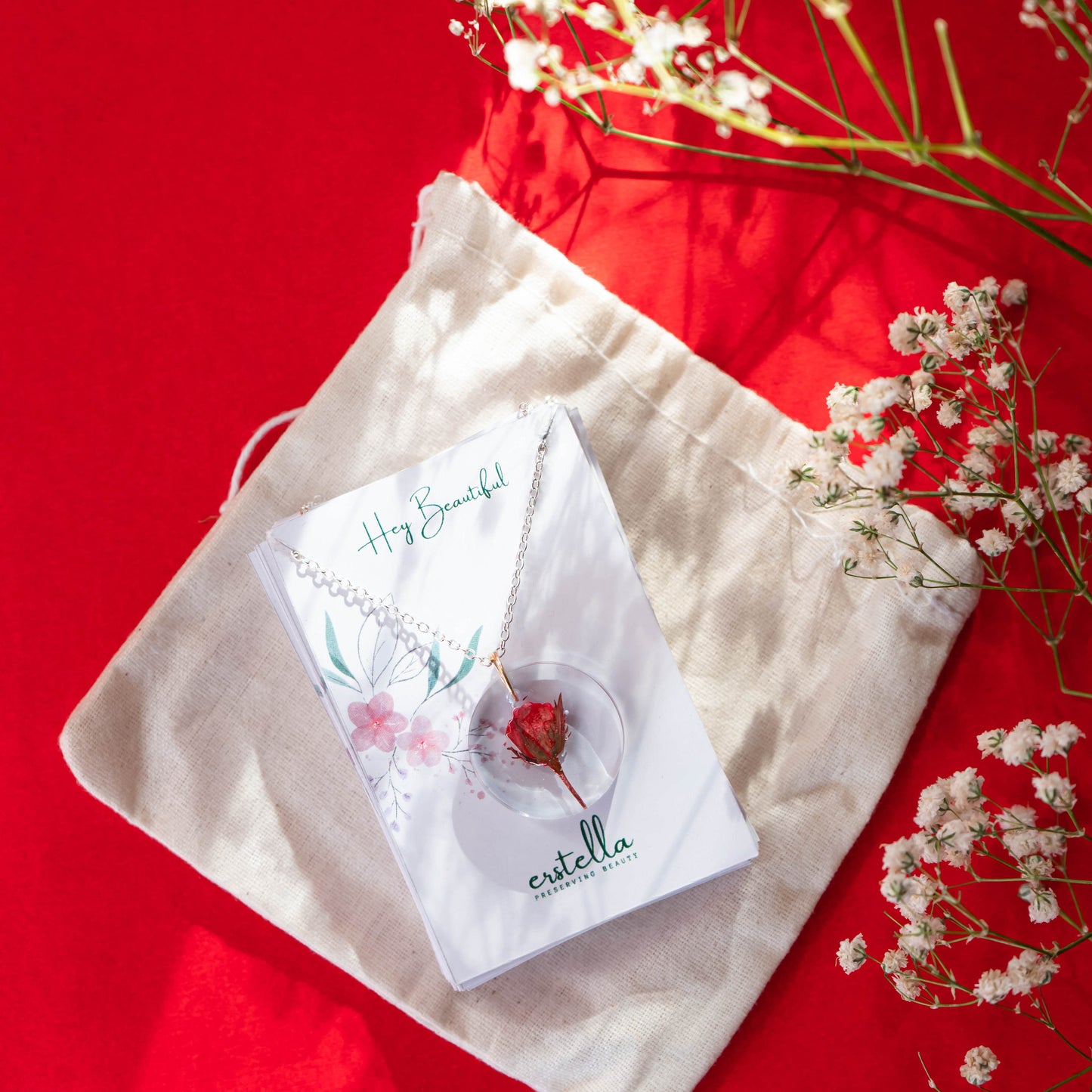 A collection of handmade resin art pendants, showcasing intricate floral designs preserved in clear resin, attached to delicate necklaces.