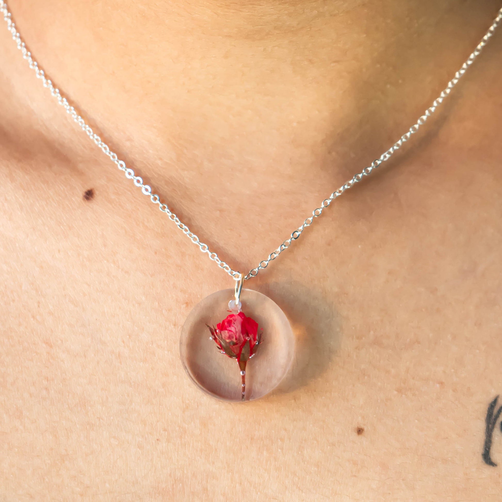 A collection of handmade resin art pendants, showcasing intricate floral designs preserved in clear resin, attached to delicate necklaces.