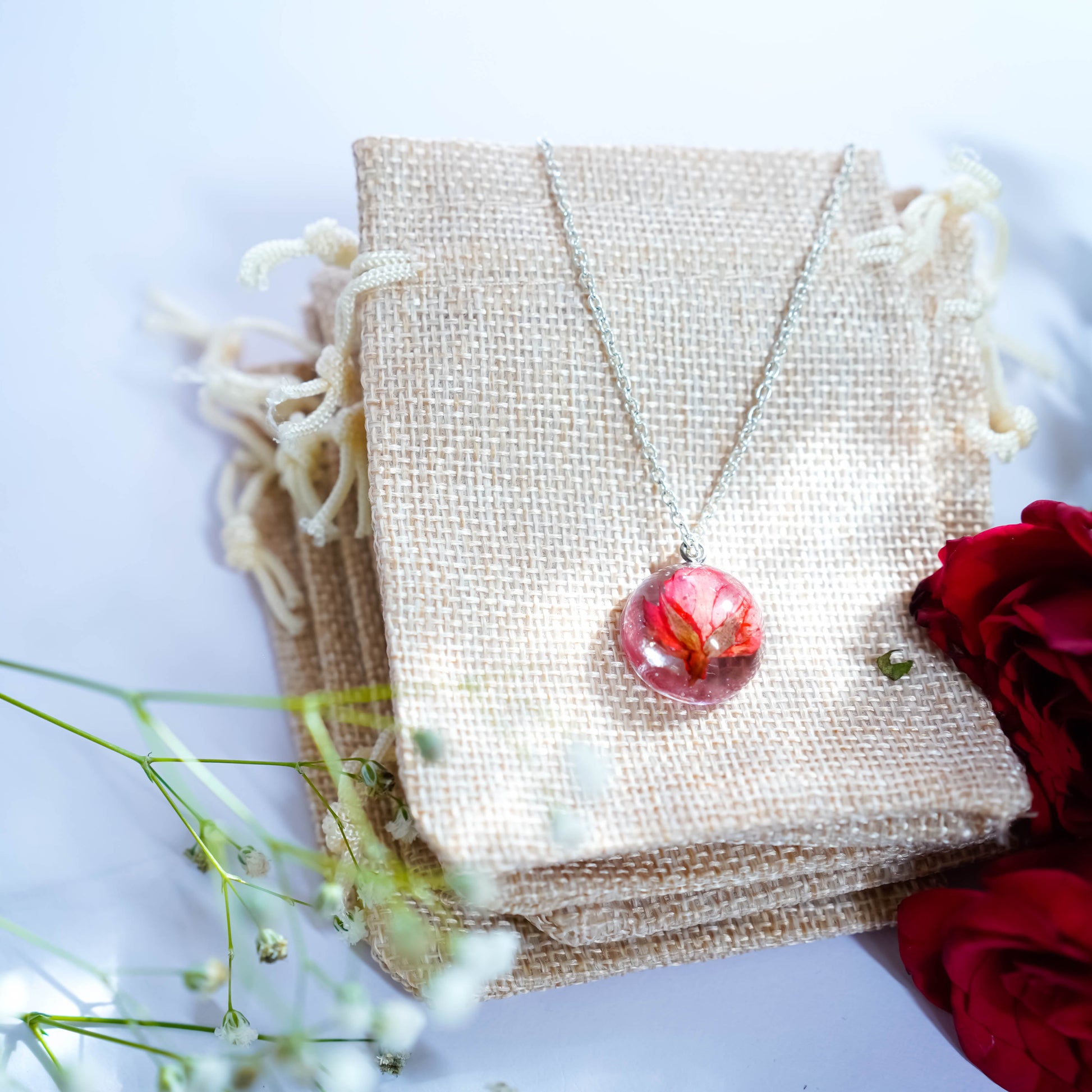 A collection of handmade resin art pendants, showcasing intricate floral designs preserved in clear resin, attached to delicate necklaces.