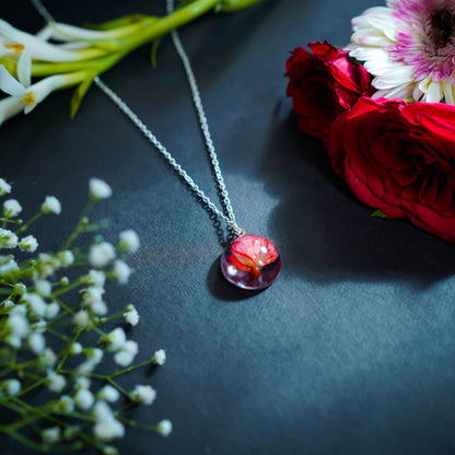 A collection of handmade resin art pendants, showcasing intricate floral designs preserved in clear resin, attached to delicate necklaces.
