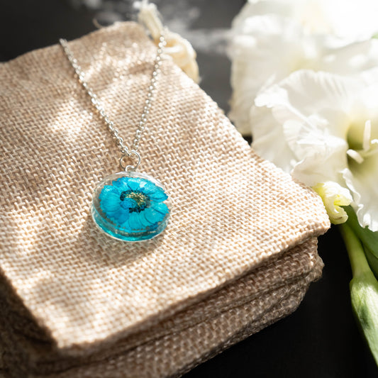 A collection of handmade resin art pendants, showcasing intricate floral designs preserved in clear resin, attached to delicate necklaces.